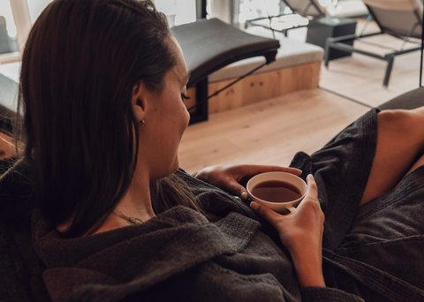 Pictures from Sportalm Woman relaxing in bathrobe drinking tea in a modern spa with a view