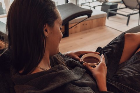 Pictures from Sportalm Woman relaxing in bathrobe drinking tea in a modern spa with a view