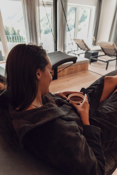 Pictures from Sportalm Woman relaxing in bathrobe drinking tea in a modern spa with a view