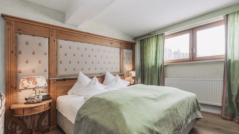 Pictures from Sportalm Cozy bedroom with green bedspread and wooden window frame