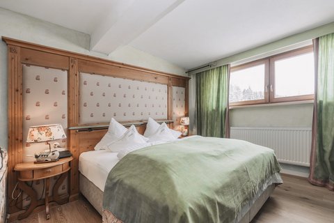 Bilder aus der Sportalm Gemütliches Schlafzimmer mit grünem Bettüberwurf und Holzfenster