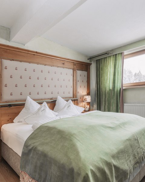 Pictures from Sportalm Cozy bedroom with green bedspread and wooden window frame