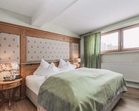 Bilder aus der Sportalm Gemütliches Schlafzimmer mit grünem Bettüberwurf und Holzfenster