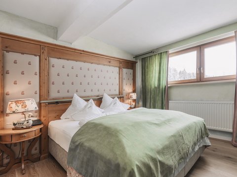 Bilder aus der Sportalm Gemütliches Schlafzimmer mit grünem Bettüberwurf und Holzfenster