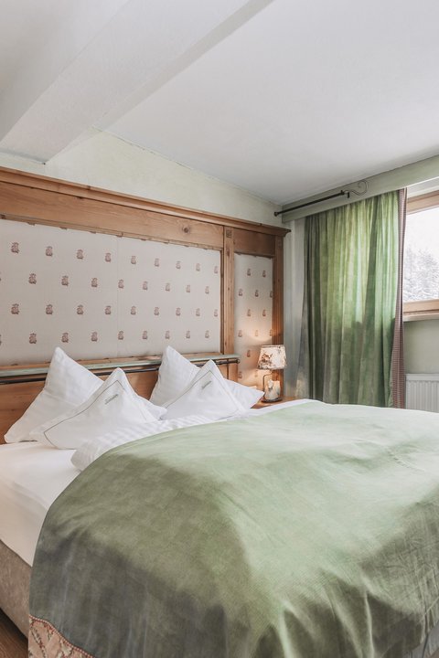 Pictures from Sportalm Cozy bedroom with green bedspread and wooden window frame