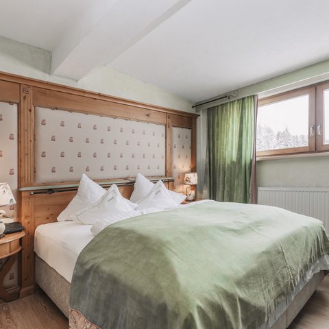 Bilder aus der Sportalm Gemütliches Schlafzimmer mit grünem Bettüberwurf und Holzfenster