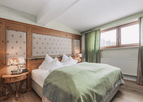 Bilder aus der Sportalm Gemütliches Schlafzimmer mit grünem Bettüberwurf und Holzfenster