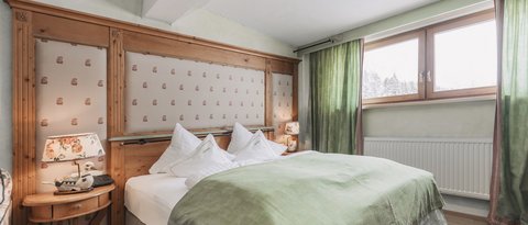 Bilder aus der Sportalm Gemütliches Schlafzimmer mit grünem Bettüberwurf und Holzfenster