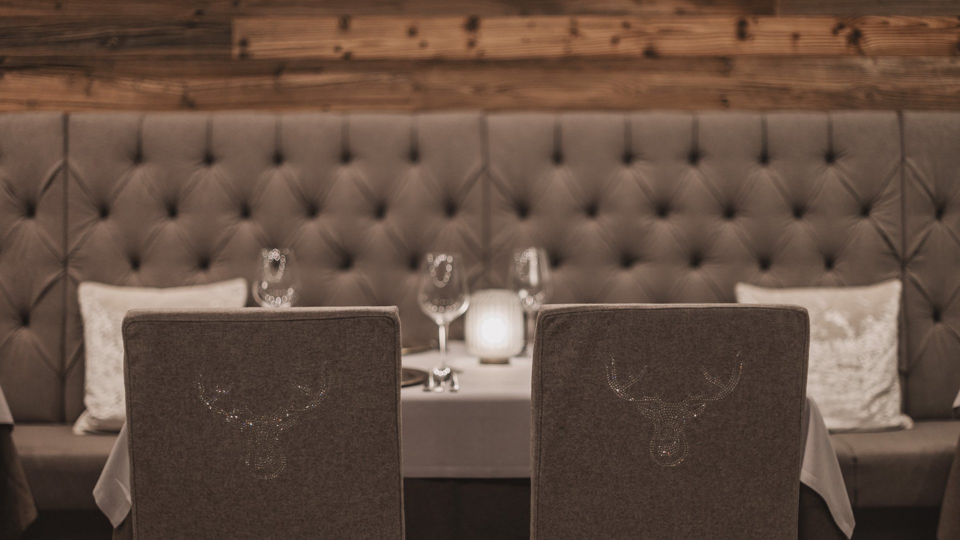 Unser Restaurant im Pitztal Elegante Restaurantstühle mit Hirschmotiv vor einer gepolsterten Bank