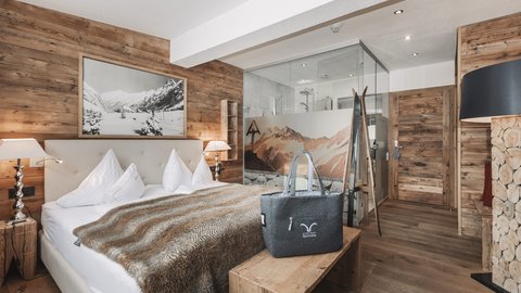Pictures from Sportalm Cozy bedroom with wooden walls, double bed, and glass shower in the background