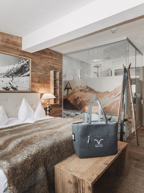 Pictures from Sportalm Cozy bedroom with wooden walls, double bed, and glass shower in the background