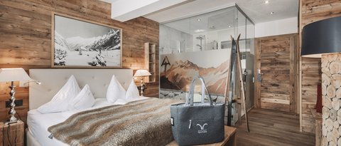 Pictures from Sportalm Cozy bedroom with wooden walls, double bed, and glass shower in the background