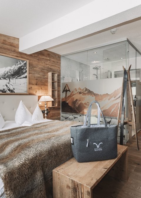 Pictures from Sportalm Cozy bedroom with wooden walls, double bed, and glass shower in the background