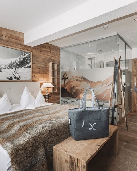Pictures from Sportalm Cozy bedroom with wooden walls, double bed, and glass shower in the background