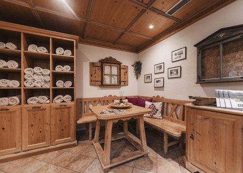 Bilder aus der Sportalm Gemütliche Holzecke mit Tisch, Bank und Regalen voller Handtücher