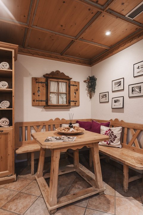 Bilder aus der Sportalm Gemütliche Holzecke mit Tisch, Bank und Regalen voller Handtücher