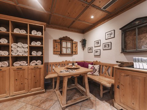 Bilder aus der Sportalm Gemütliche Holzecke mit Tisch, Bank und Regalen voller Handtücher