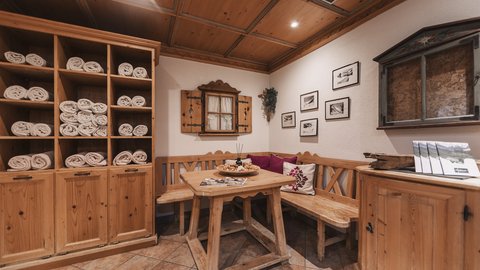 Bilder aus der Sportalm Gemütliche Holzecke mit Tisch, Bank und Regalen voller Handtücher