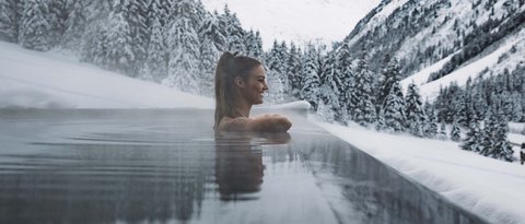 Pictures from Sportalm Woman relaxing in heated outdoor pool with snowy mountains in the background