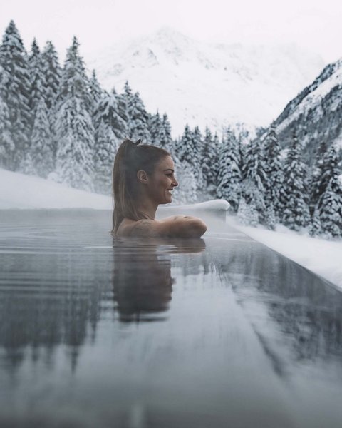 Pictures from Sportalm Woman relaxing in heated outdoor pool with snowy mountains in the background