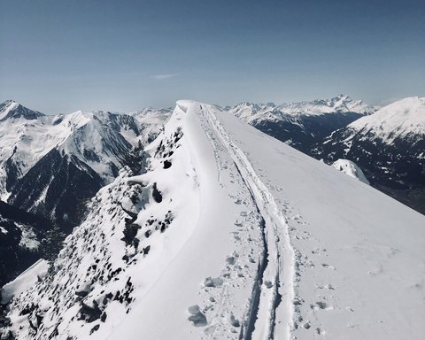 Bilder aus der Sportalm Schnee bedeckter Berggipfel mit Skispuren unter klarem Himmel