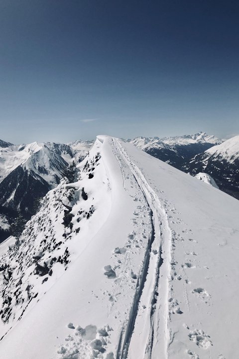 Bilder aus der Sportalm Schnee bedeckter Berggipfel mit Skispuren unter klarem Himmel