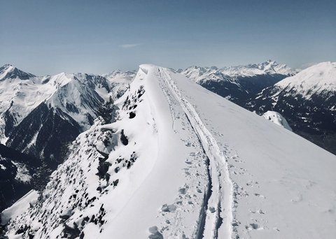 Bilder aus der Sportalm Schnee bedeckter Berggipfel mit Skispuren unter klarem Himmel
