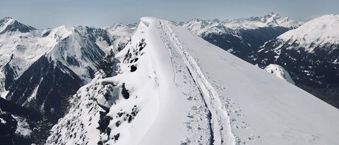Bilder aus der Sportalm Schnee bedeckter Berggipfel mit Skispuren unter klarem Himmel
