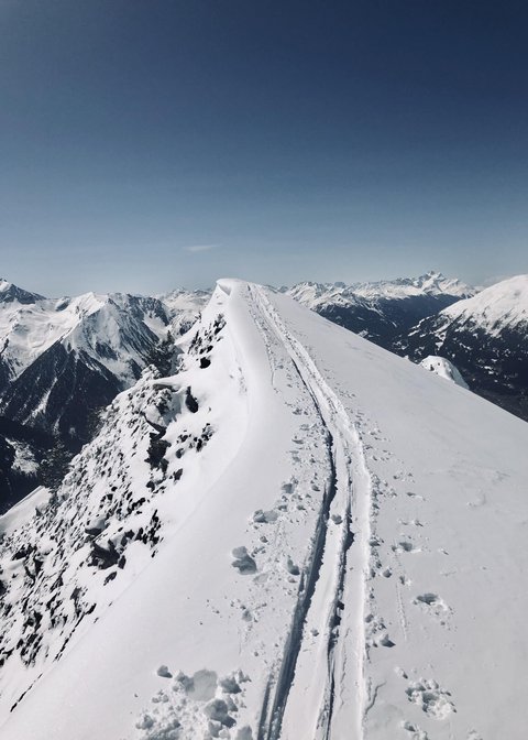 Bilder aus der Sportalm Schnee bedeckter Berggipfel mit Skispuren unter klarem Himmel