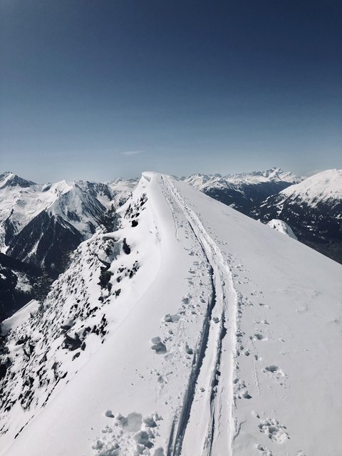 Bilder aus der Sportalm Schnee bedeckter Berggipfel mit Skispuren unter klarem Himmel