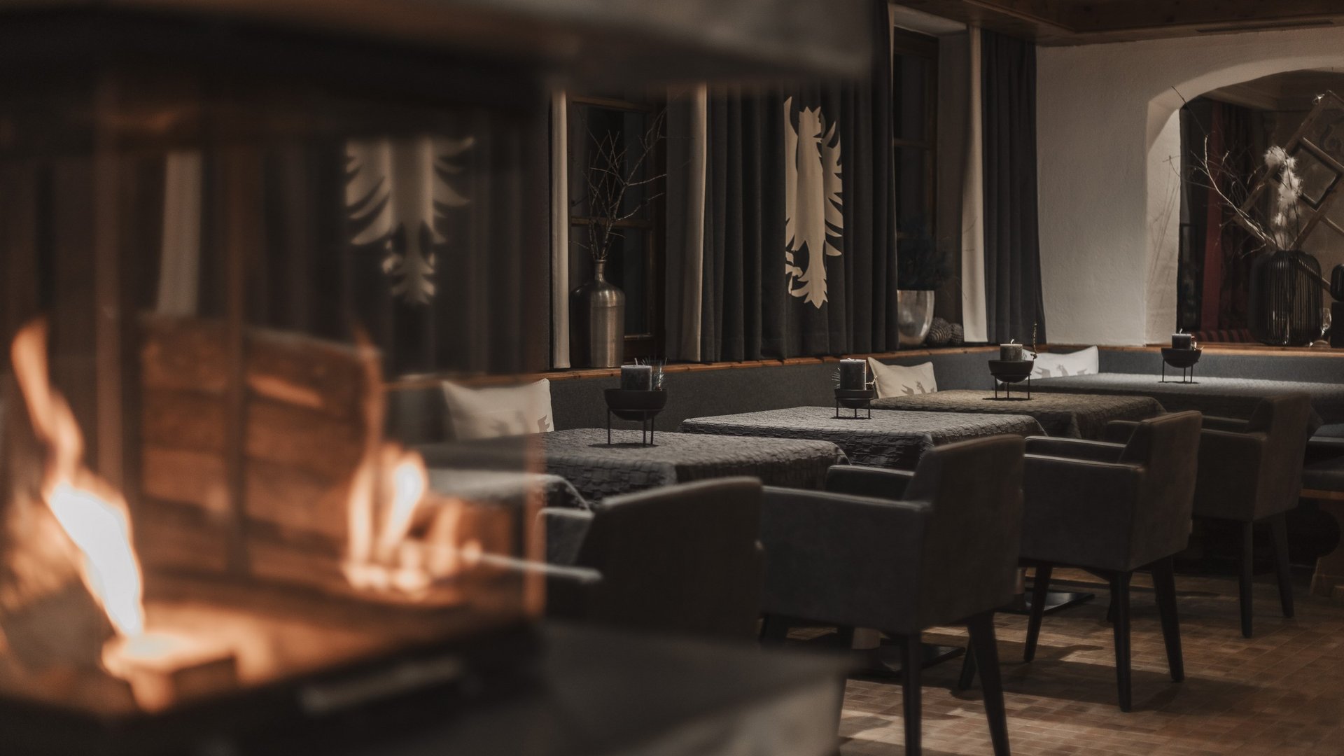 Freude schenken Gemütlicher Essbereich mit Kamin und dunkelgrauen Sesseln in warmem Licht