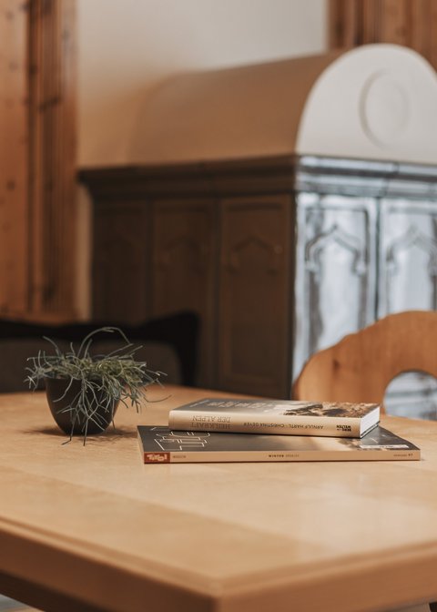 Bilder aus der Sportalm Holztisch mit Büchern und Pflanze in gemütlichem Raum