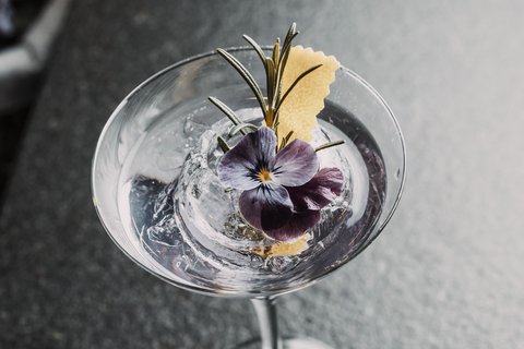 Pictures from Sportalm Cocktail with ice, purple flower and rosemary sprig in martini glass
