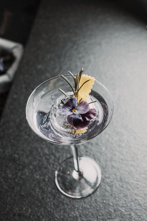 Bilder aus der Sportalm Cocktail mit Eis, Rosenblüte und Rosmarinzweig in Martiniglas