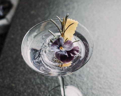 Bilder aus der Sportalm Cocktail mit Eis, Rosenblüte und Rosmarinzweig in Martiniglas