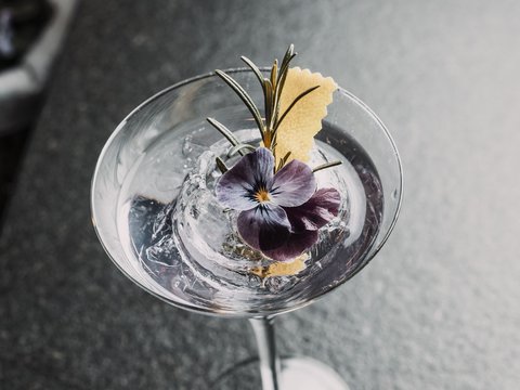 Bilder aus der Sportalm Cocktail mit Eis, Rosenblüte und Rosmarinzweig in Martiniglas