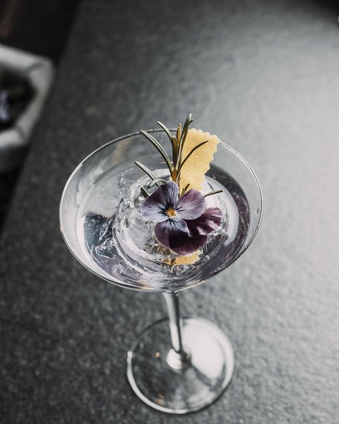Bilder aus der Sportalm Cocktail mit Eis, Rosenblüte und Rosmarinzweig in Martiniglas
