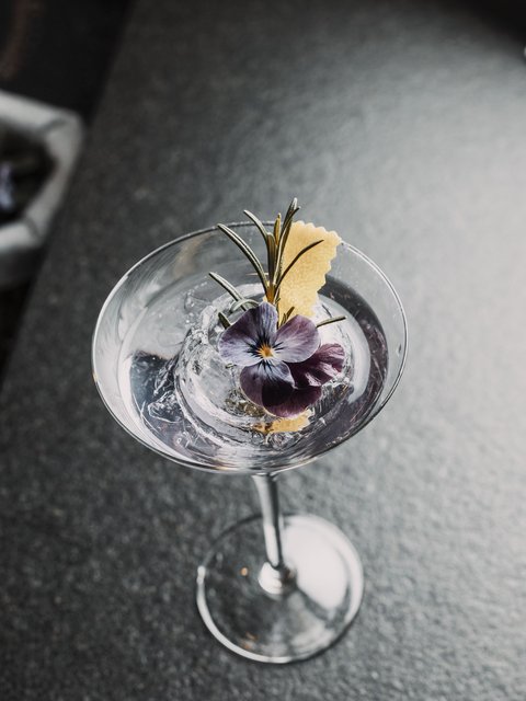Bilder aus der Sportalm Cocktail mit Eis, Rosenblüte und Rosmarinzweig in Martiniglas