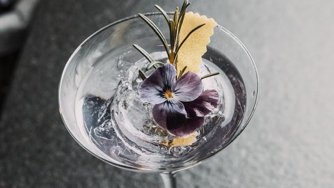 Bilder aus der Sportalm Cocktail mit Eis, Rosenblüte und Rosmarinzweig in Martiniglas