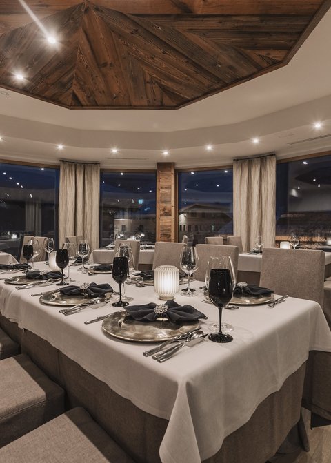 Bilder aus der Sportalm Elegantes Restaurant mit gedecktem Tisch und Holzelementen bei Abendbeleuchtung