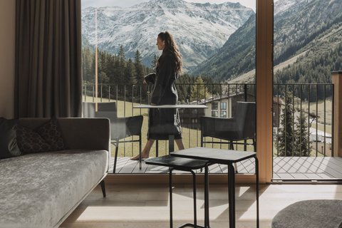 Pictures from Sportalm Woman on balcony overlooking snowy mountains from modern living room
