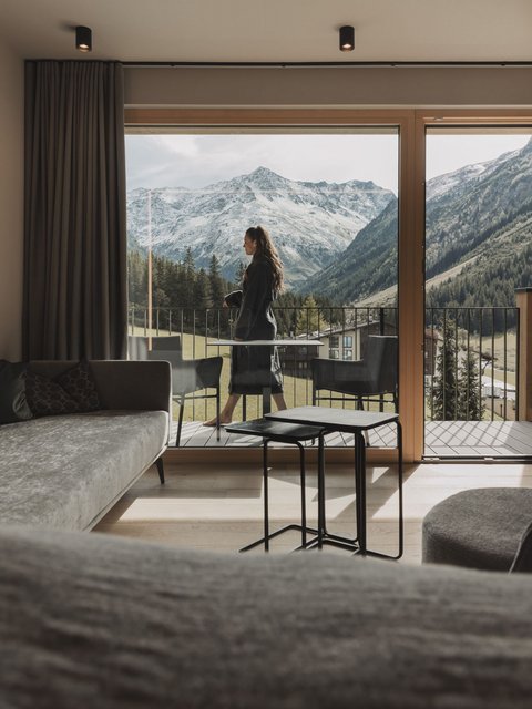 Pictures from Sportalm Woman on balcony overlooking snowy mountains from modern living room