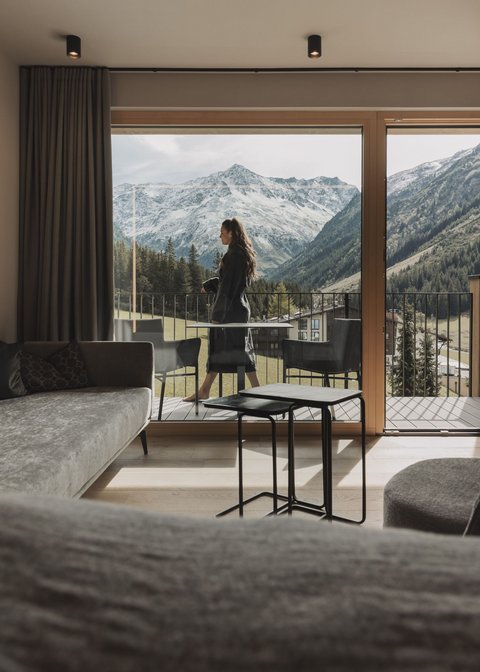 Bilder aus der Sportalm Frau auf Balkon mit Blick auf schneebedeckte Berge von modernem Wohnzimmer