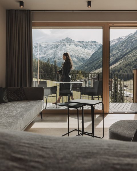 Pictures from Sportalm Woman on balcony overlooking snowy mountains from modern living room