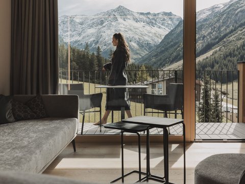 Pictures from Sportalm Woman on balcony overlooking snowy mountains from modern living room