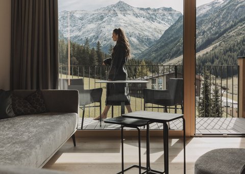 Bilder aus der Sportalm Frau auf Balkon mit Blick auf schneebedeckte Berge von modernem Wohnzimmer