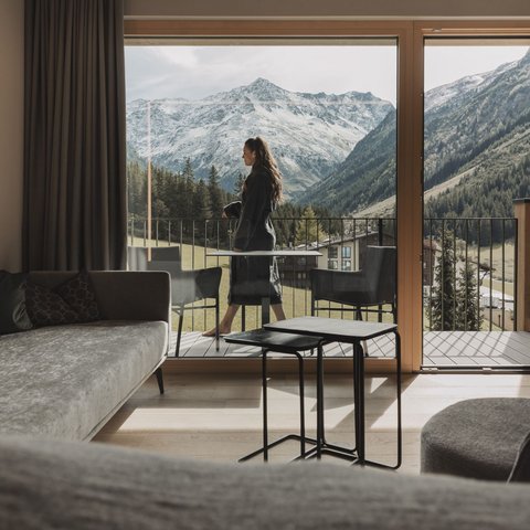Pictures from Sportalm Woman on balcony overlooking snowy mountains from modern living room
