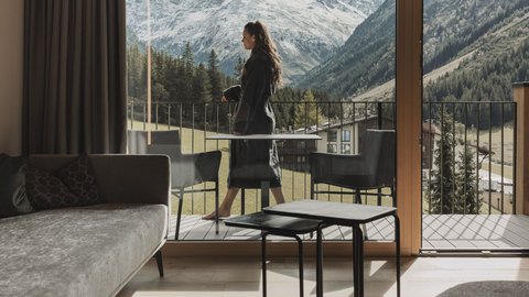 Bilder aus der Sportalm Frau auf Balkon mit Blick auf schneebedeckte Berge von modernem Wohnzimmer