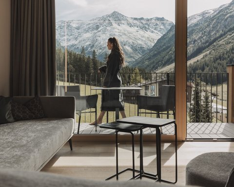 Bilder aus der Sportalm Frau auf Balkon mit Blick auf schneebedeckte Berge von modernem Wohnzimmer