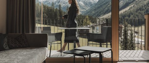 Pictures from Sportalm Woman on balcony overlooking snowy mountains from modern living room